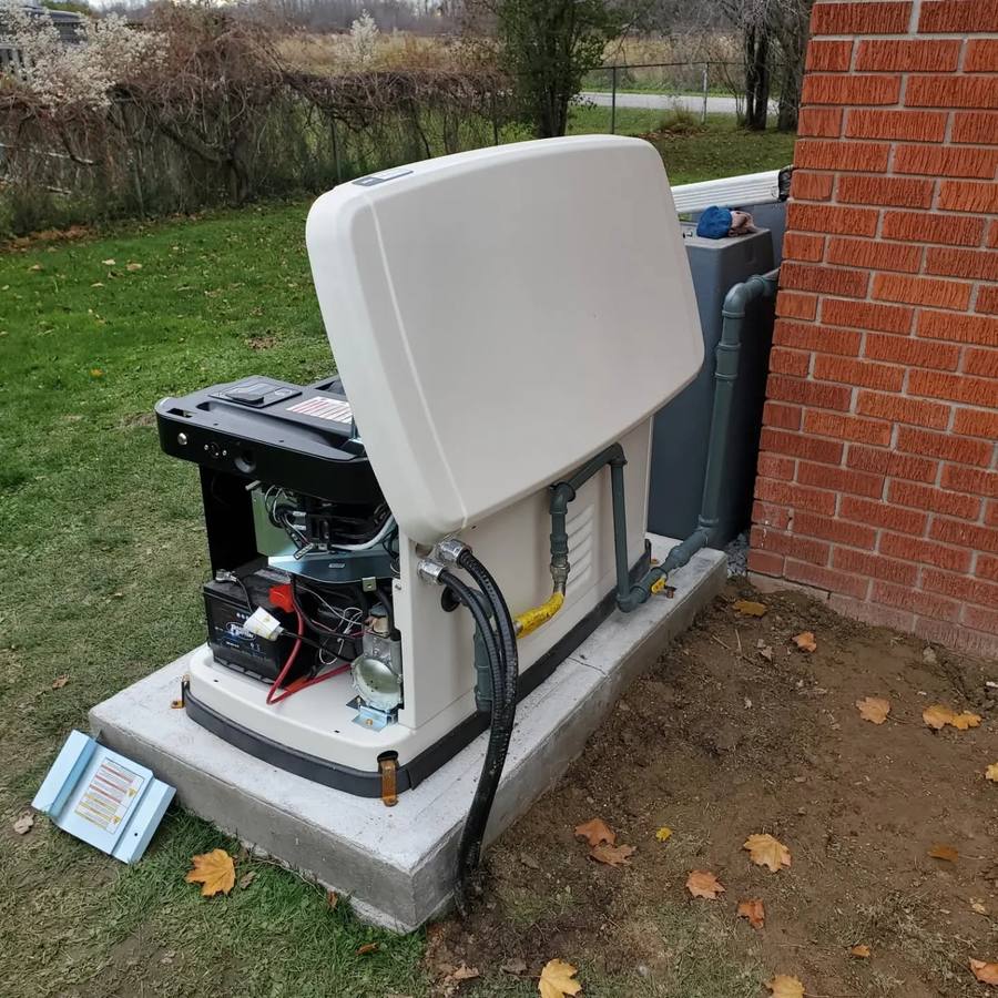 Standby generator with its lid open showing the battery, controls, and gas line connections